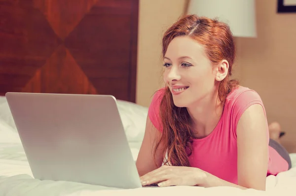 Donna felice che lavora sul computer portatile sdraiato nel letto — Foto Stock