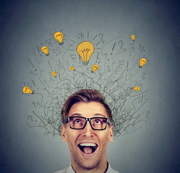 Hombre feliz en gafas mirando hacia arriba con bombilla idea de luz por encima de la cabeza — Foto de Stock