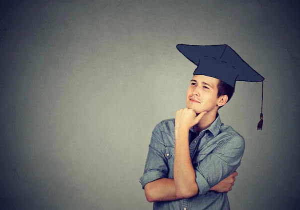 Graduate student mannen i keps klänning tittar upp tänkande — Stockfoto