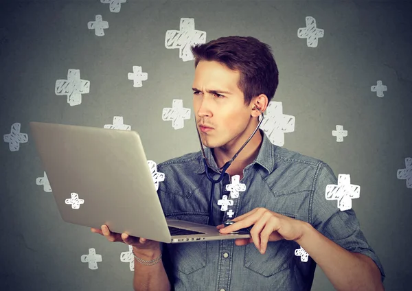 Hombre que escucha la computadora con estetoscopio mirando PC portátil . —  Fotos de Stock