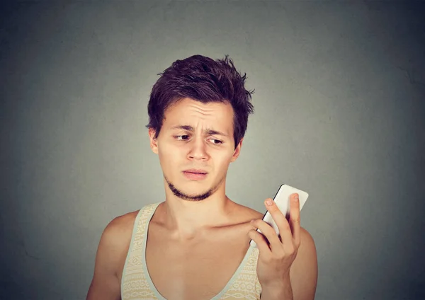 Роздратований чоловік тримає мобільний телефон, дивлячись божевілля на стресові тексти — стокове фото