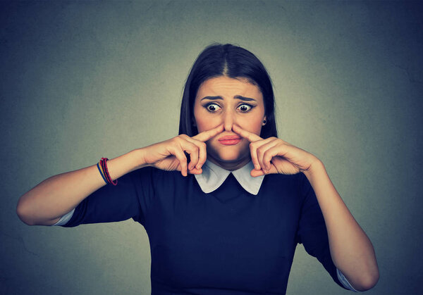 woman pinches nose looks with disgust something stinks bad smell 