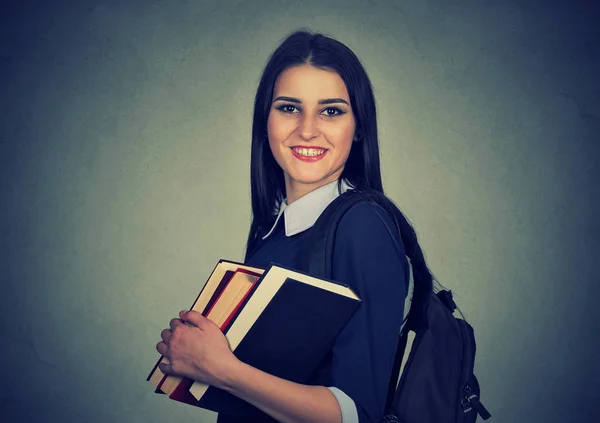 Estudiante sonriente llevando mochila y sosteniendo pila de libros — Foto de Stock