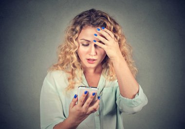 Upset woman holding cellphone disgusted with message she received  clipart