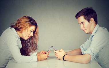 Sinir bozucu rahatsız genç kadın ve smartphone ile masada oturan adam 