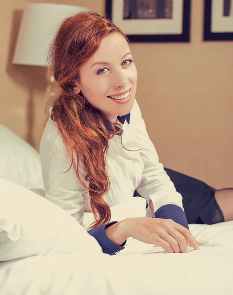 Atractiva joven sonriente mujer acostada en la cama y mirando a la cámara —  Fotos de Stock