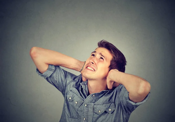 Роздратований стресовий чоловік прикриває вуха, дивлячись вгору — стокове фото
