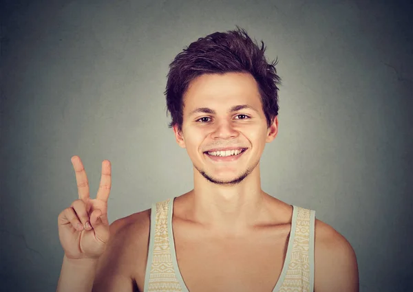 Молодой человек, симпатичный студент держит победу мира, два знака — стоковое фото