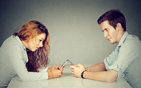 Frustrado molesto joven mujer y hombre sentado a la mesa con teléfono inteligente — Foto de Stock