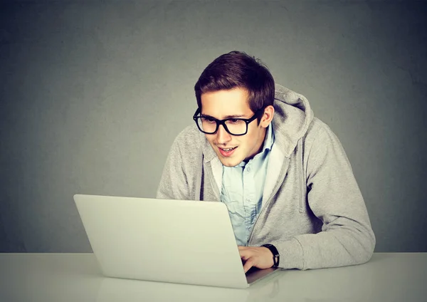 Joven usando un portátil sentado en la mesa — Foto de Stock