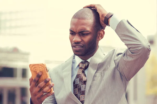 Uomo stressato che tiene il cellulare guardando lo schermo con espressione faccia a croce — Foto Stock