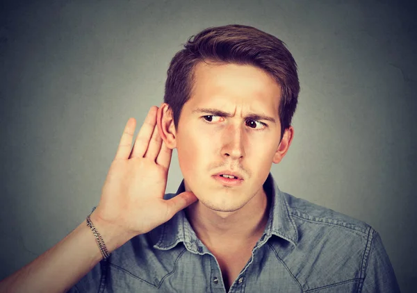 Hard of hearing man putting hand on ear listening to gossip — стоковое фото