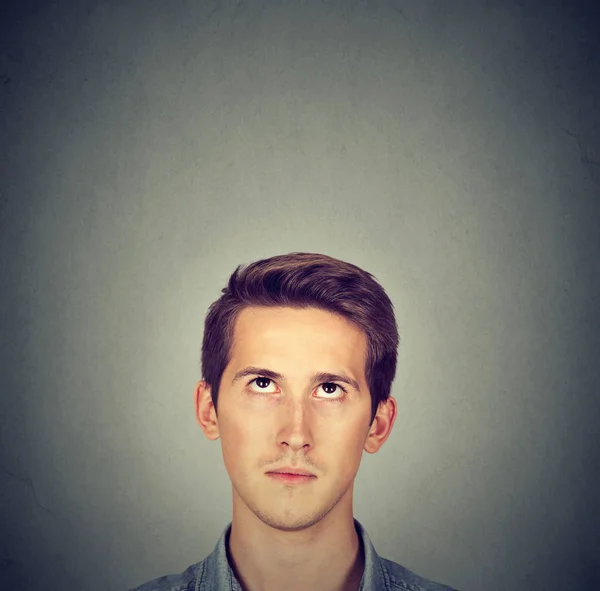Человек смотрит на серый фон с копировальным пространством над головой — стоковое фото