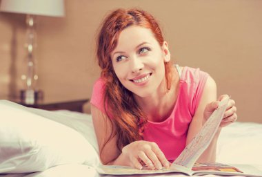 bir dergi okurken yatakta yatan kadın