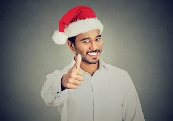 Sonriente excitado hombre en rojo santa sombrero dando pulgares hacia arriba signo —  Fotos de Stock