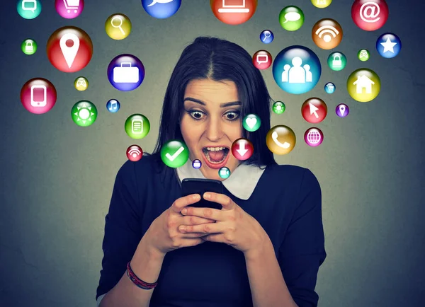 Surprised woman using smartphone social media icons flying out screen — Stock Photo, Image