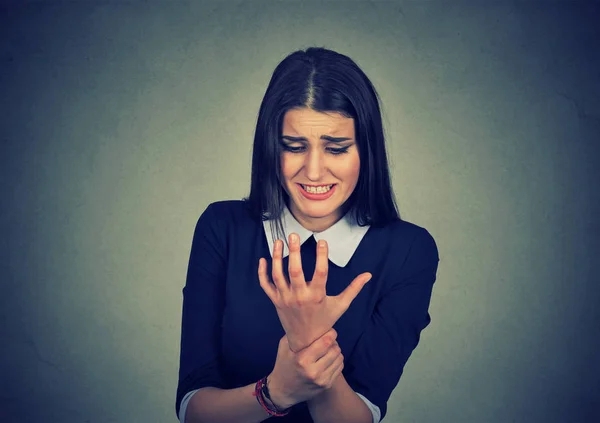 Junge Frau hält ihr schmerzhaftes Handgelenk rot gefärbt. Verstauchungsschmerzen — Stockfoto