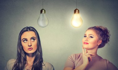 Two women thinking looking up at light bulbs. clipart