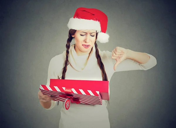 Kvinna i jultomten hatt öppna gåva upprörd visar tummen ner — Stockfoto