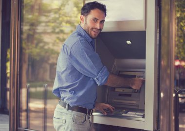 ATM kullanan genç ve mutlu adam.