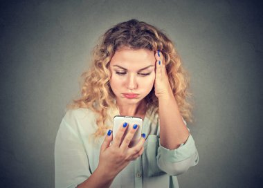 annoyed young woman, pissed off by what she saw on her cell phone  clipart