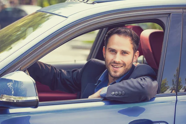 Glücklich lächelnder junger Mann am Steuer seines neuen Autos. — Stockfoto