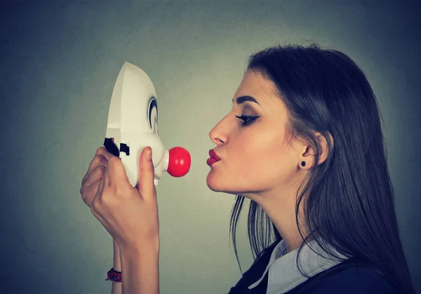 Jovem mulher beijando máscara de palhaço — Fotografia de Stock