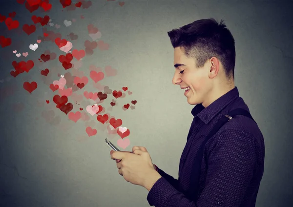 Man sending love messages on mobile phone hearts flying away — Stock Photo, Image