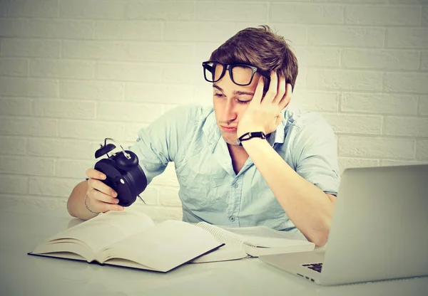 Sleepy man met boek laptopcomputer kijken wekker — Stockfoto