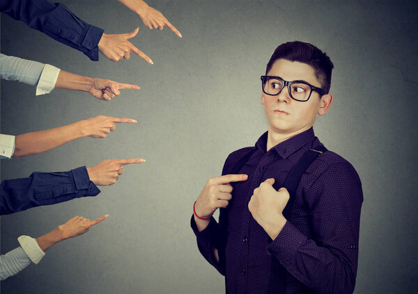 Беспокойный человек, которого обвиняют люди, указывающие на него пальцем.
