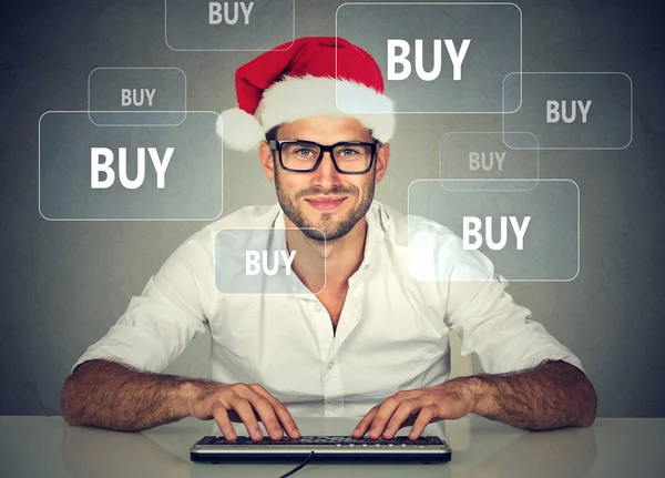 Happy christmas man in red santa claus hat buying stuff online — Stock Photo, Image