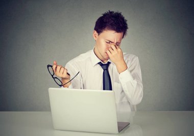 Laptop ile masada oturan gözünü ovuşturarak yorgun iş adamı 