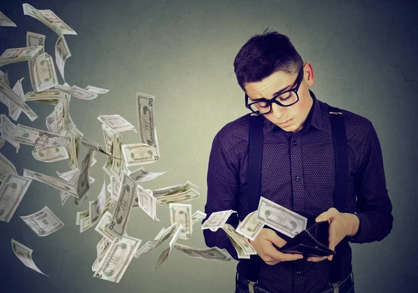 Trauriger Mann blickt auf Geldbörse mit Geld-Dollar-Scheinen, die davonfliegen — Stockfoto