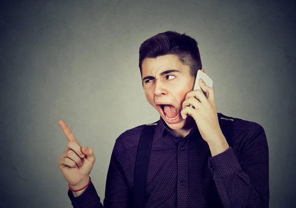 Сердитий молодий чоловік кричить на мобільному телефоні — стокове фото