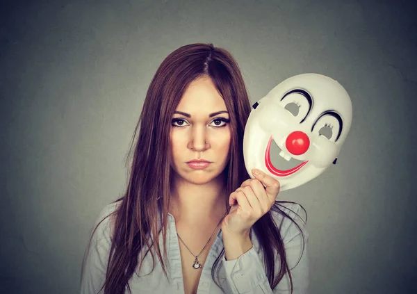 Upprörd orolig kvinna med sorgligt uttryck lyfter clown mask — Stockfoto