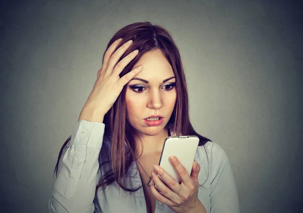 Verärgerte Frau blickt besorgt auf Handy mit Nachricht, die sie erhalten hat — Stockfoto