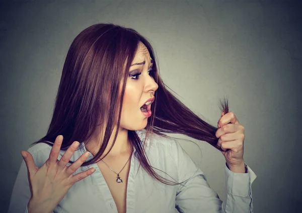 Frustrada mujer sorprendida de que está perdiendo el pelo notado puntas abiertas — Foto de Stock