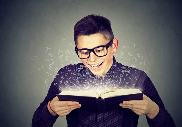 Hombre leyendo un libro con letras del alfabeto que salen — Foto de Stock