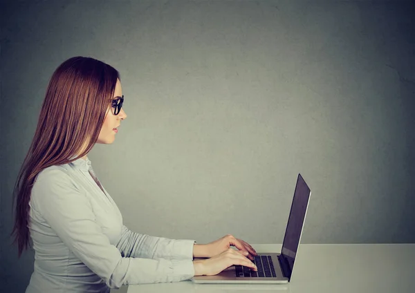 Junge Frau sitzt am Tisch und arbeitet am Laptop — Stockfoto