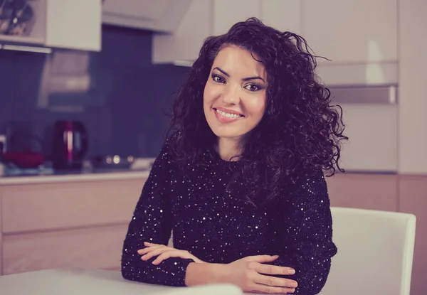 Mulher sorrindo para a câmera enquanto sentado em casa na cozinha — Fotografia de Stock