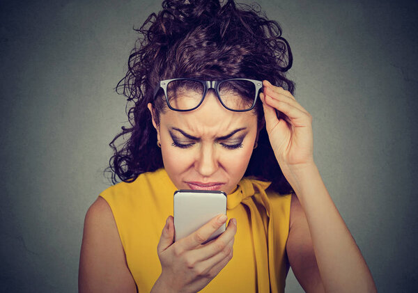 woman with glasses having trouble seeing cell phone vision problems