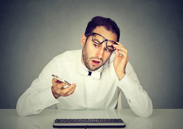 Chockad man pratar telefon sitter vid bord med tangentbord — Stockfoto