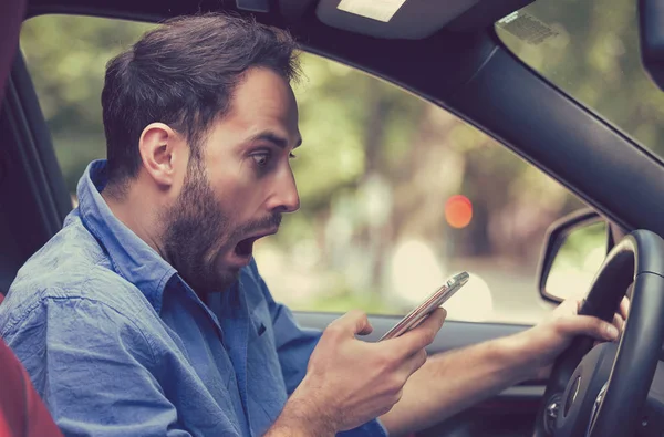 Hombre sentado dentro del coche con mensajes de texto del teléfono móvil mientras conduce —  Fotos de Stock