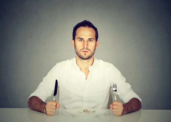 Mann mit Gabel und Messer sitzt mit leerem Teller am Tisch — Stockfoto