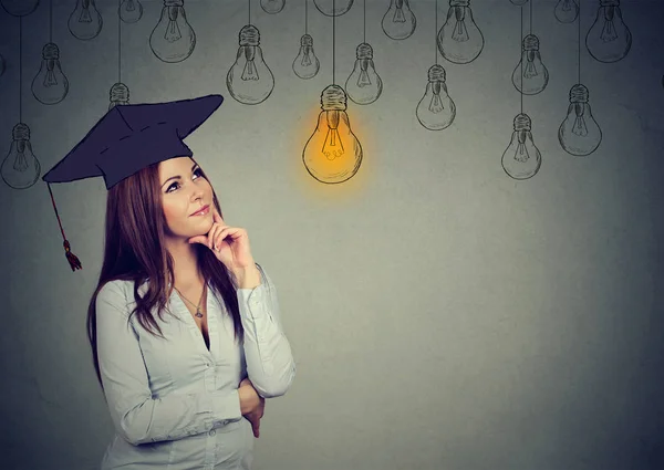 Estudiante graduado reflexivo mirando hacia arriba en la bombilla brillante — Foto de Stock