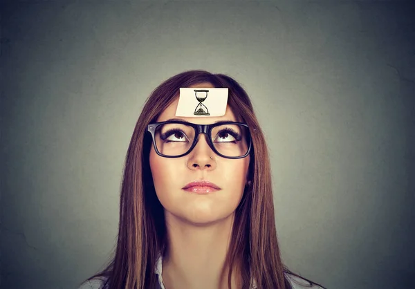 Denkende Frau mit Sanduhr-Aufkleber auf der Stirn. Zeitmanagement-Konzept — Stockfoto