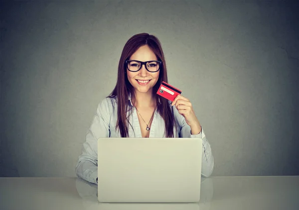 Mulher mostrando um cartão de crédito e usando laptop navegando na internet — Fotografia de Stock
