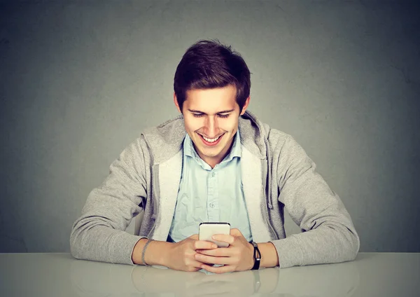 Happy man using mobile phone sitting at table — Stock Photo, Image