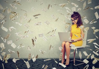 Online iş aşağı düşen para nakit yapmaya bina bir dizüstü bilgisayar kullanan genç kadın