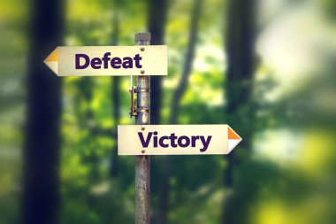 Tabelasını ters yönde zafer ve yenilgi işaret eden oklar ile bir parkta 